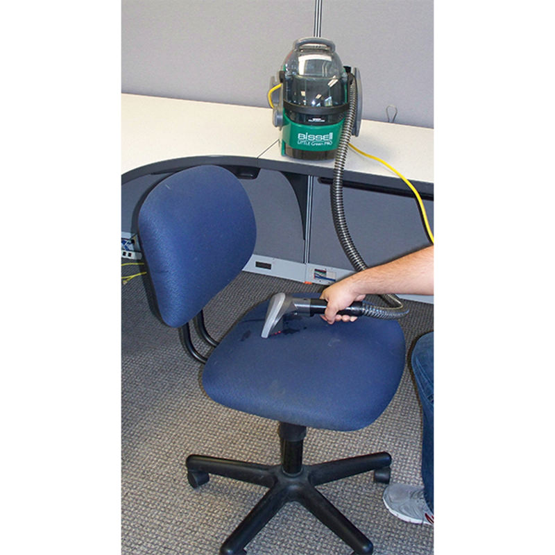 Woman using Bissell BGU1451T bagged upright vacuum to clean a chair.