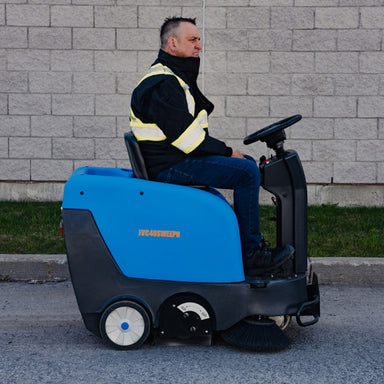 Man riding the Johnny Vac Industrial Ride-On Sweeper Machine JVC40SWEEPN on the road
