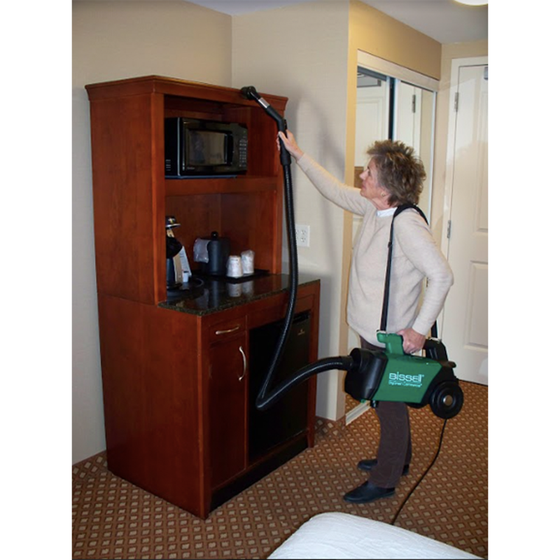 Woman cleaning furniture with a vacuum on white background, demonstrating its effectiveness on upholstery.