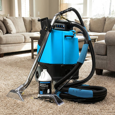 Realistic living room scene featuring the Mytee 220PSI heated extractor on plush carpet with comfortable couches and natural lighting.